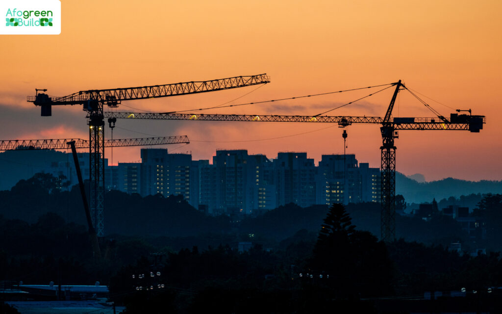 Cranes silhouetted against a cityscape at sunset.